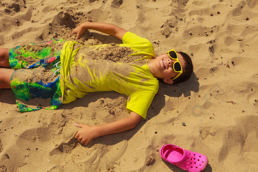 男孩在海边玩得开心假期概念上的活跃时间年轻的小男孩在海边沙滩上玩