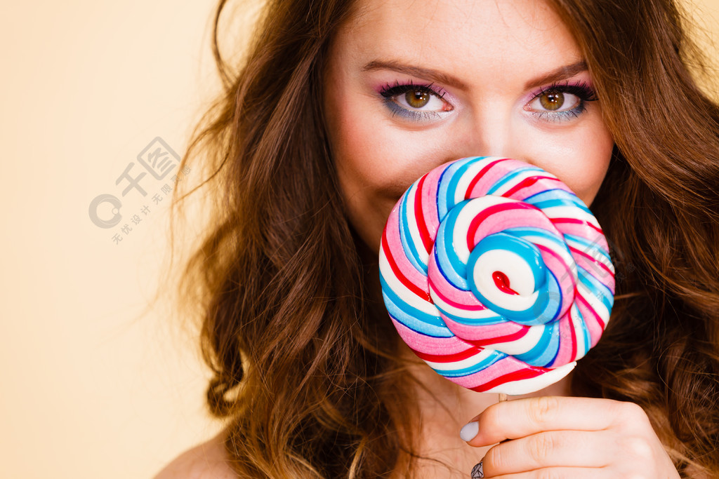 女人迷人的女孩五颜六色的眼睛组成了手里拿着大棒棒糖糖果遮住了她的