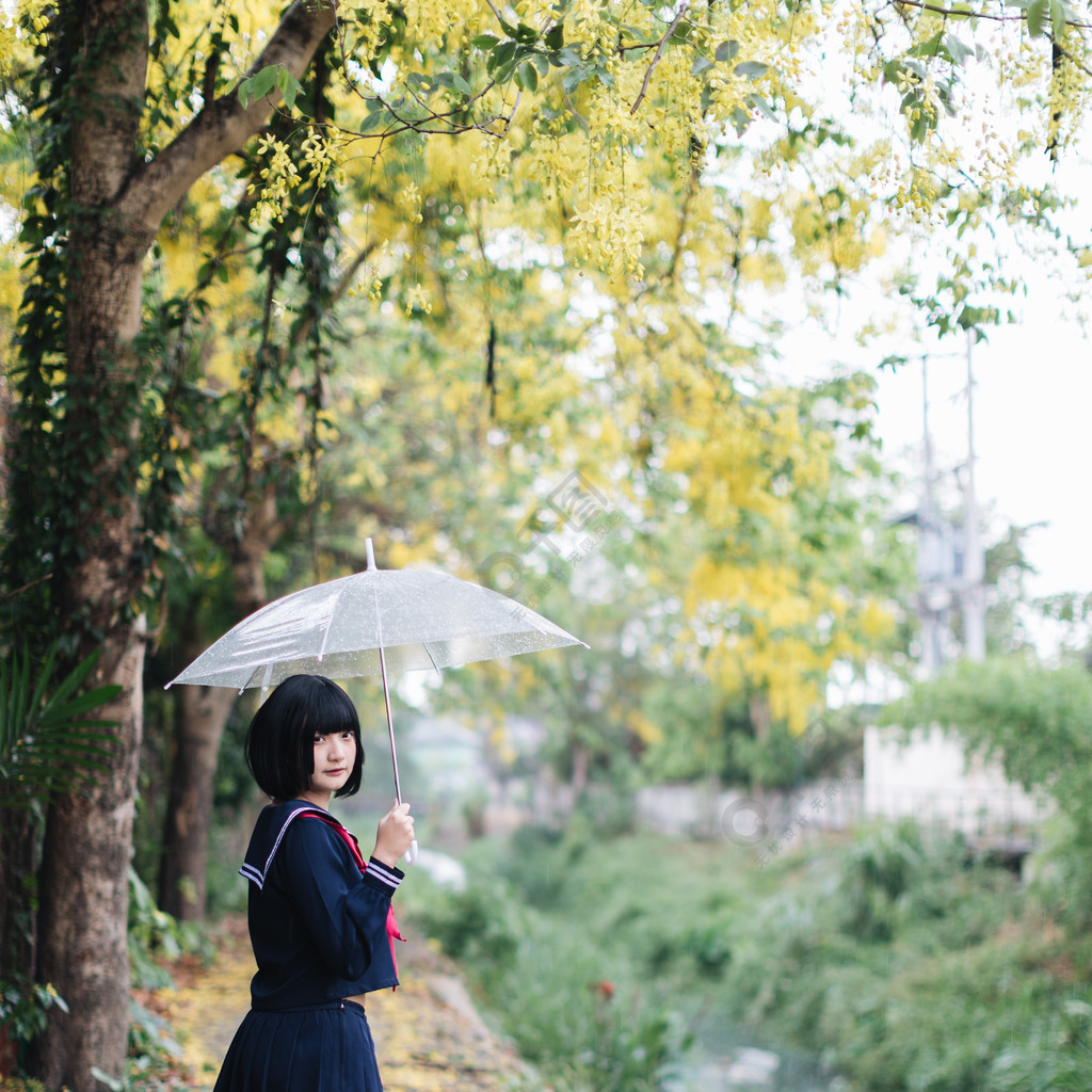 下雨時在自然人行道上撐傘行走的亞洲女學生畫像