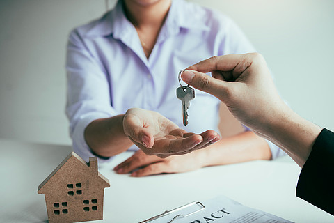房地产经纪人的手通过买方房屋概念将钥匙传递给办公室的新房主