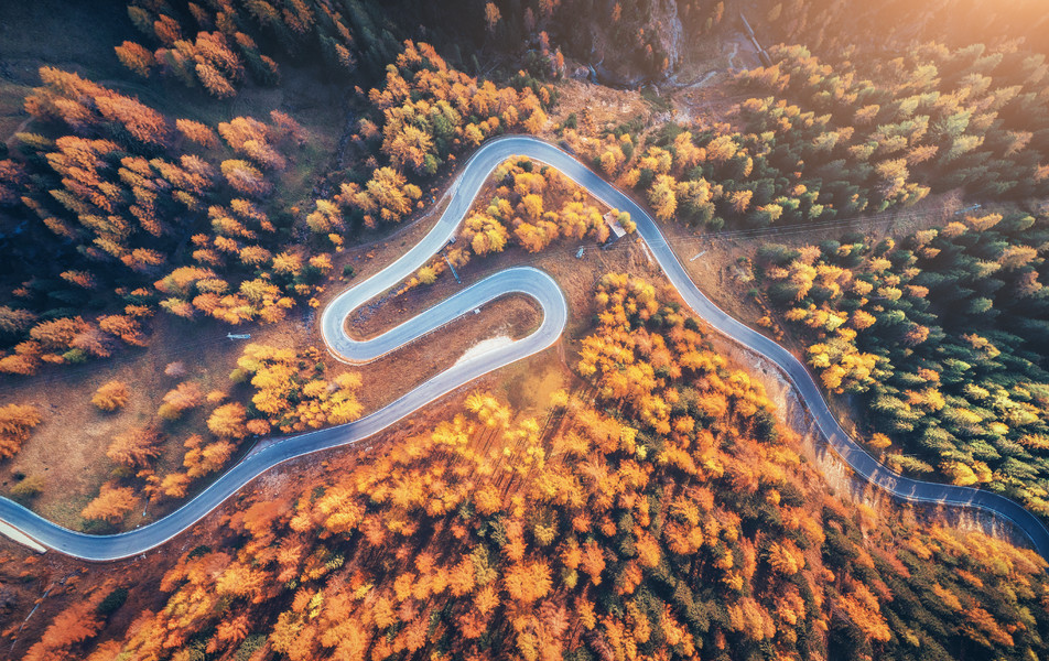 山中日落时分在秋天的森林中蜿蜒曲折的道路鸟瞰 i
