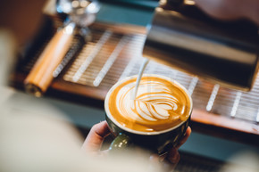 咖啡师制作拿铁艺术，在一杯牛奶和咖啡中拍摄焦点，复古滤镜图像