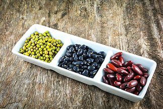 全谷物种子各种扁豆与绿豆、黑豆和红芸豆谷物混合在木背景的白杯中