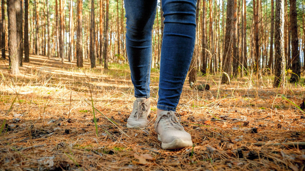 女性游客脚在森林地面上行走的特写图像女性游客脚在森林地面上行走的