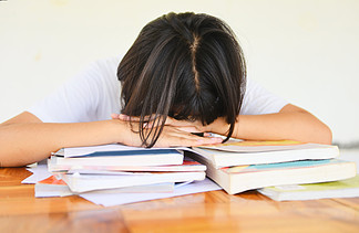 考试压力/教育年轻女大学生在课堂上记笔记并使用铅笔坐学习概念强调亚洲女学生参加考试期末并睡在书上