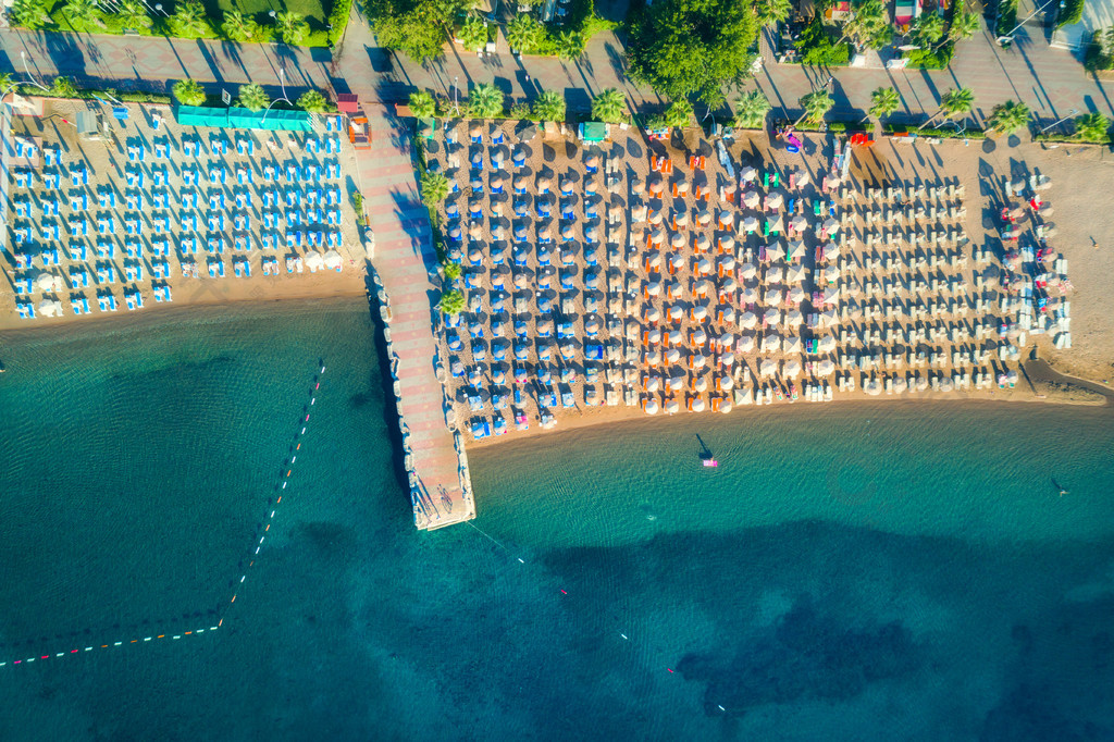 躺椅船隻綠樹酒店建築物的鳥瞰圖從無人機的夏季海景頂視圖透明綠松石