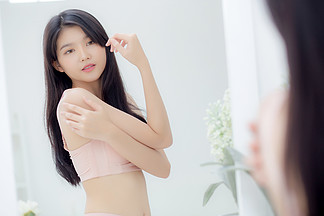 美丽性感的年轻亚洲女性看镜子在肩上涂抹奶油和信息，美丽的女孩涂抹润肤露护肤以<i>保</i>持健康和柔软的水合作用，治疗和化妆品与<i>保</i><i>湿</i>剂。