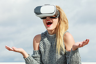 年轻女子在外面测试 VR 眼镜。春季天气时，女性佩戴虚拟现实耳机。在外面戴 VR 的女人