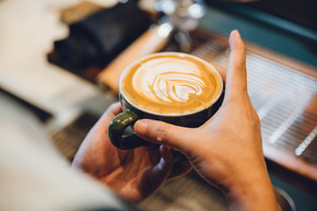 咖啡师制作拿铁艺术，在一杯牛奶和咖啡中拍摄焦点，复古滤镜图像