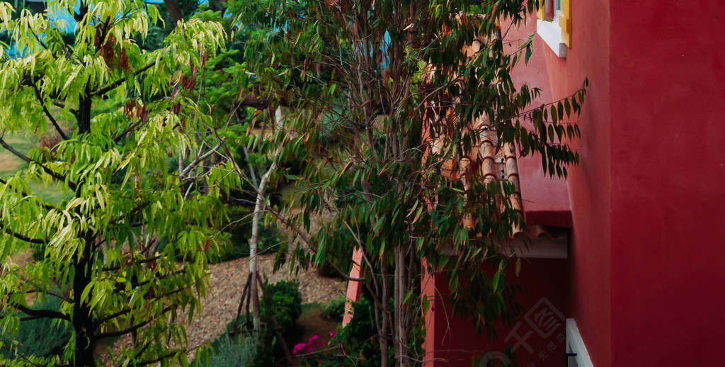 2014 年 8 月 4 日，泰国华欣 — 色彩缤纷的红色地中海风格乡间别墅瓷砖屋顶建筑，带大树花园