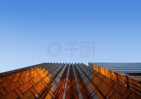 金色的建筑，蓝天。现代办公摩天大楼的窗户玻璃。立面设计。城市景观背景的建筑外观。