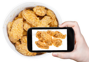 拍摄食物概念 — 游客在美国智能手机上拍摄篮子里的热炸鸡翅
