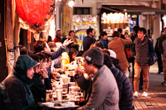 2018 年 11 月 29 日，日本东京 — 上野区 Ameyoko 市场充<i>满</i>活力的繁忙美食街夜生活，焦点模糊的游客在街边居酒屋餐厅吃喝