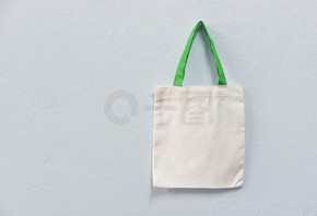 白色手提帆布面料生态袋布购物袋在墙壁背景/零废物使用少塑料说没有塑料袋污染问题概念