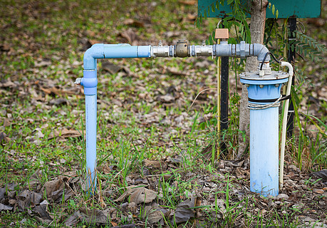 绿草地上带 pvc 管和系统电动深井潜水泵水的地下水井