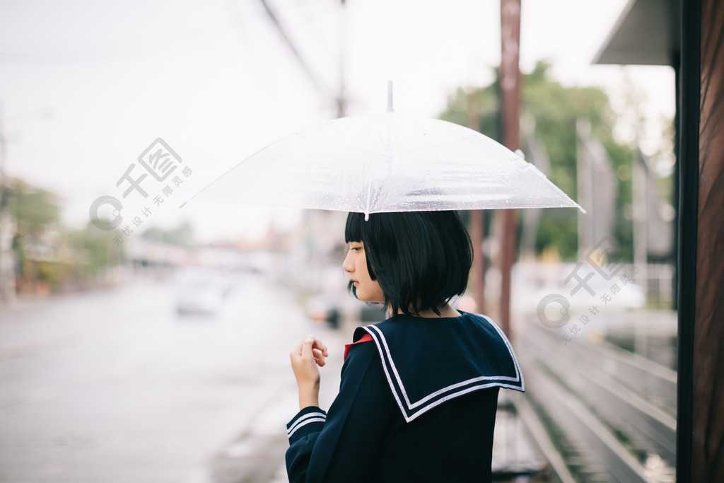 下雨時在自然人行道上撐傘行走的亞洲女學生畫像