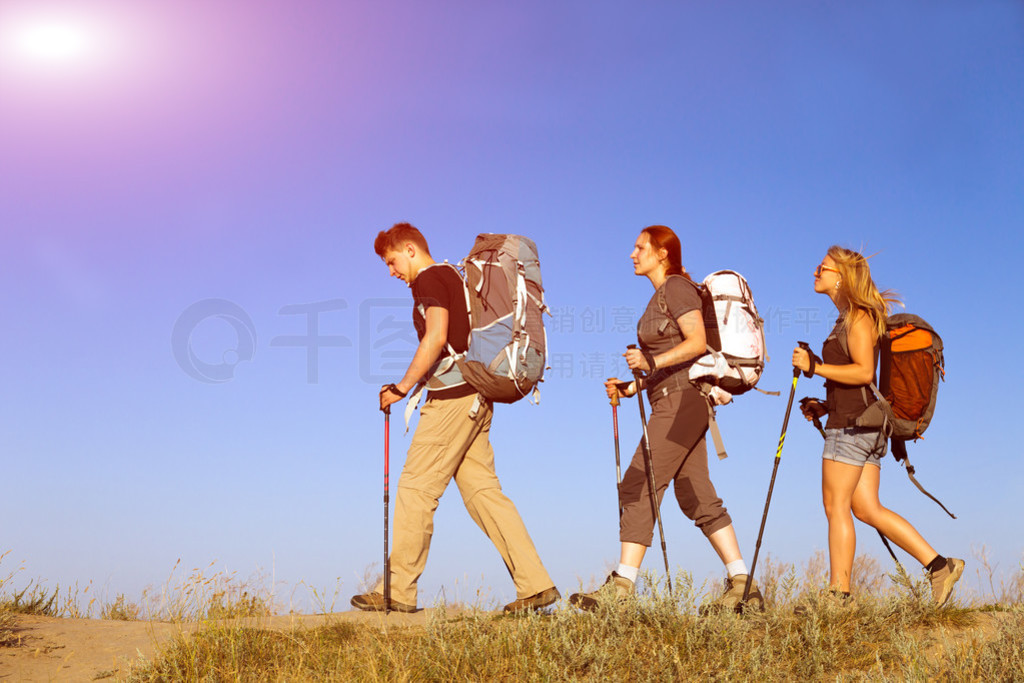 Group of hikers walks on grassy lawn