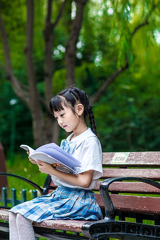 坐在公里椅子上看书的小学生