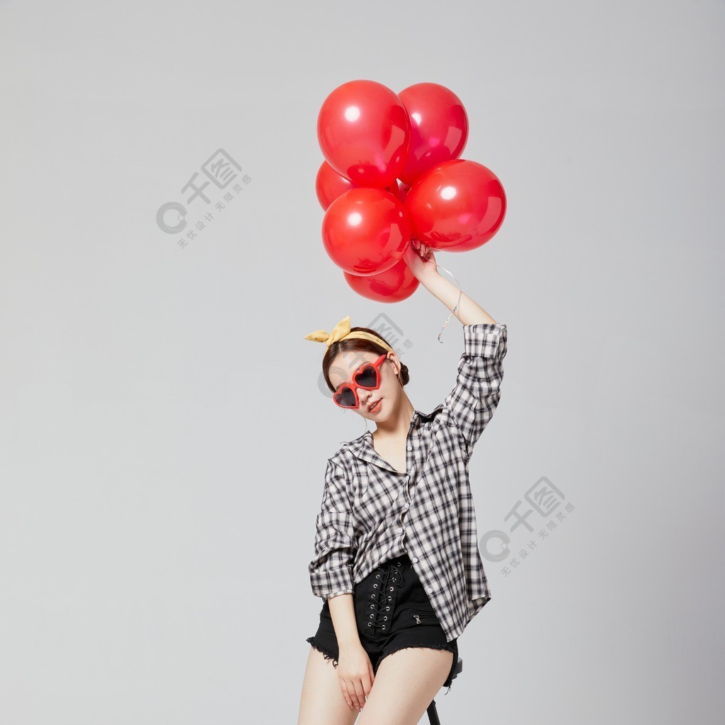 年轻活力女性拿着一个红气球坐在椅子上