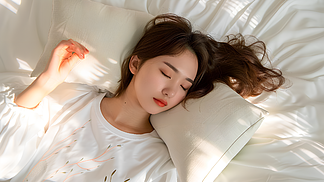 世界睡眠日头顶上拍摄的年轻中国女子躺在床上,侧身睡觉枕头在她的