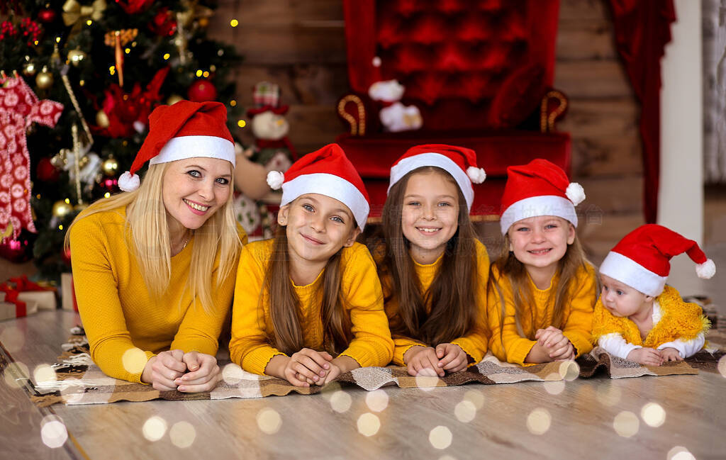 Mom and children in red hats on the background of the Christmas