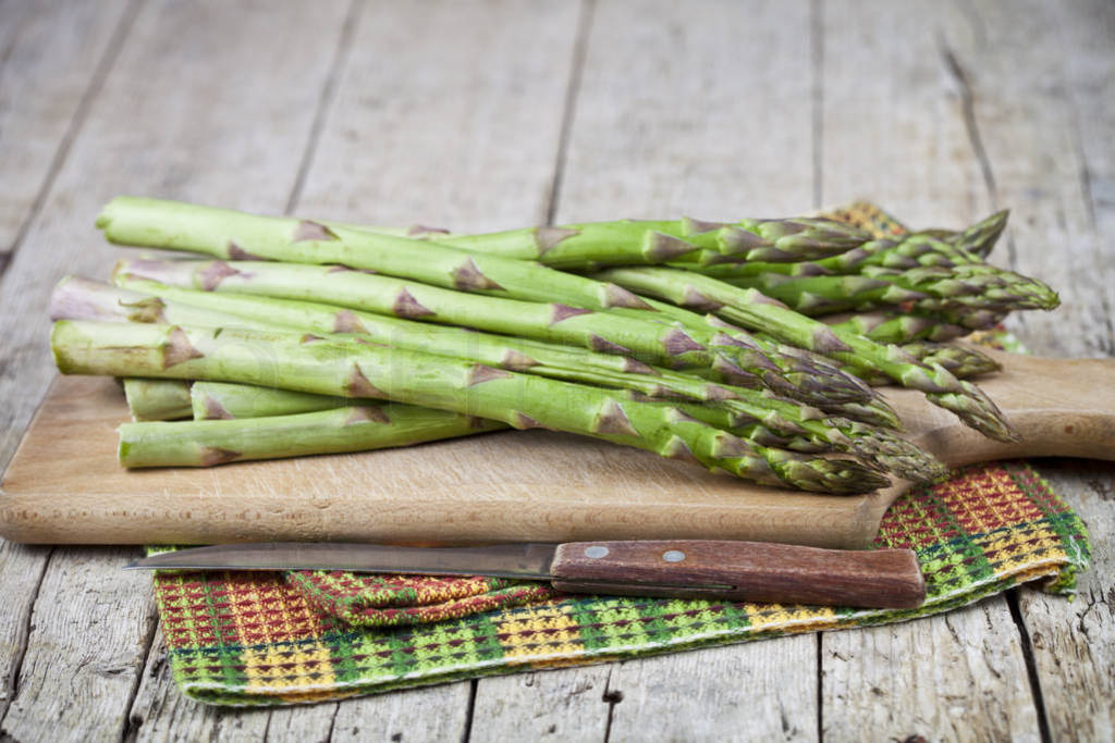 Organic raw garden asparagus and knife closeup on cutting board