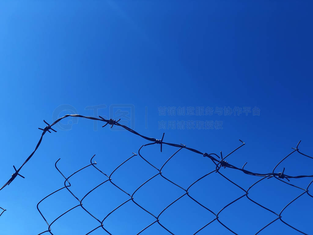 Background of a barbwire fence against a blue sky