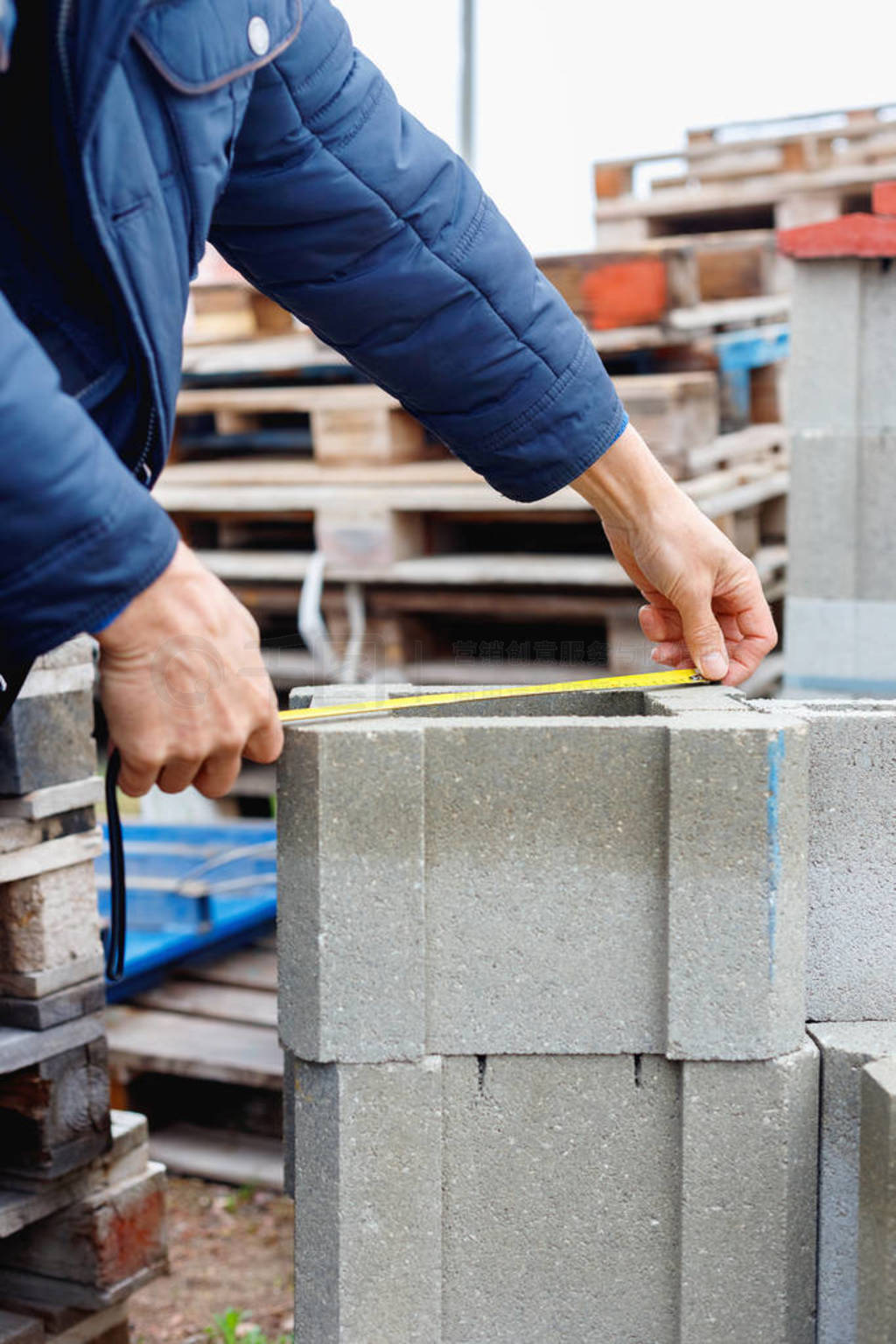 Worker measures cement building blocks on the warehouse
