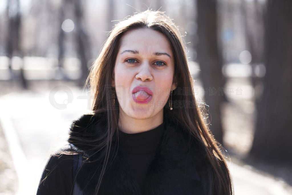 Young woman shows her tongue.