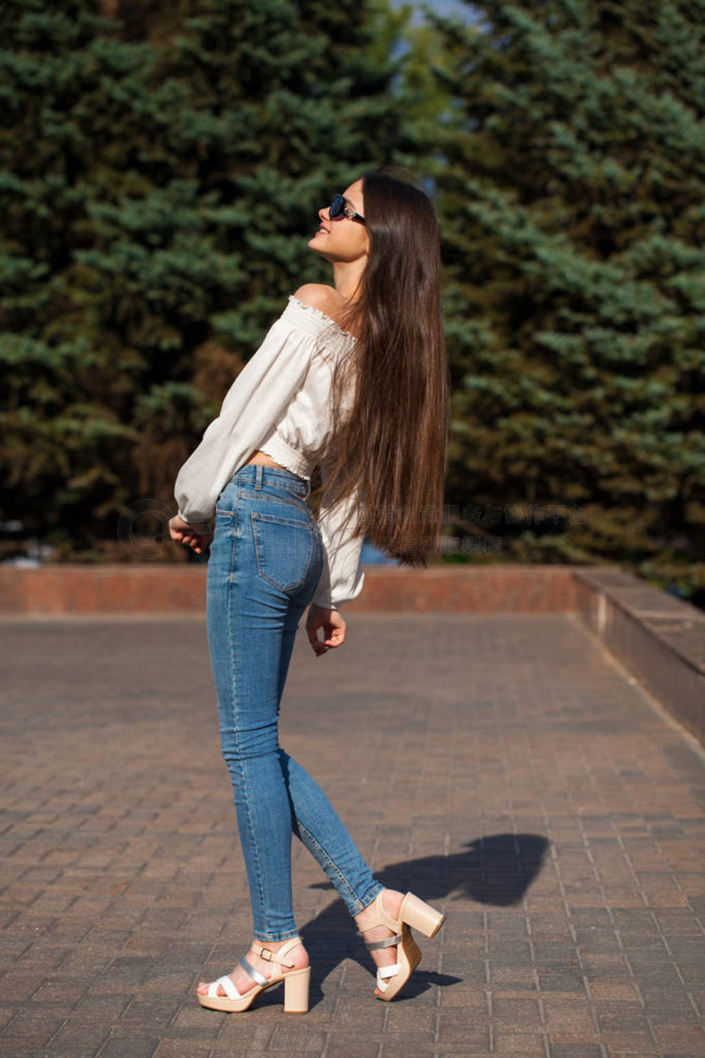 Pretty stylish brunette girl in blue jeans and white blouse