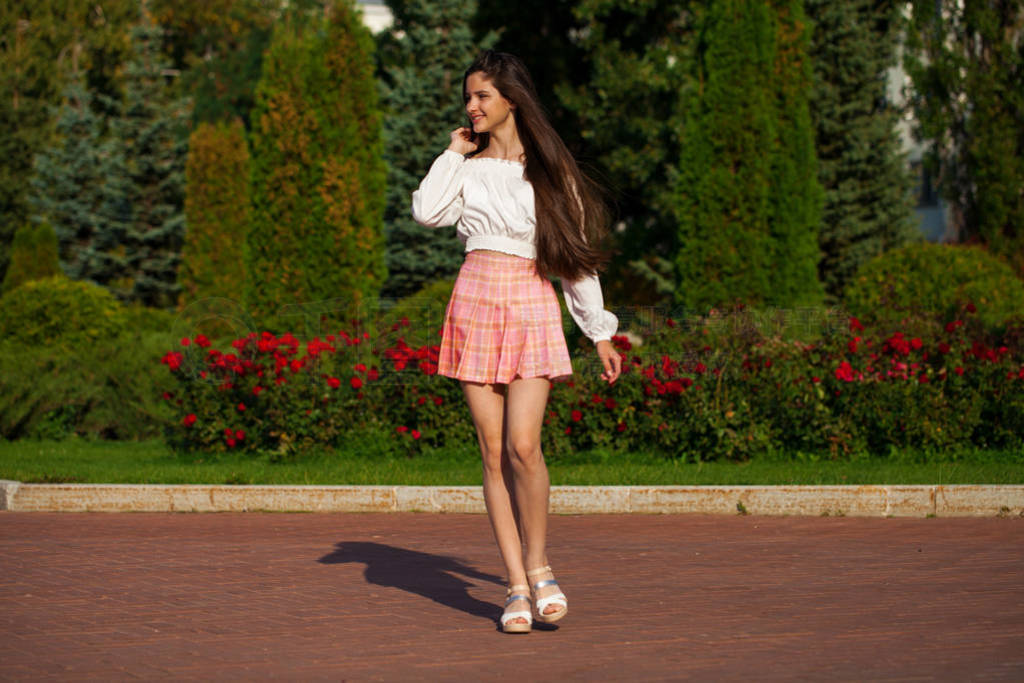 Pretty stylish brunette girl in plaid skirt and white blouse