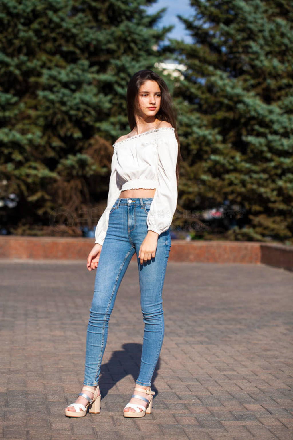 Pretty stylish brunette girl in blue jeans and white blouse