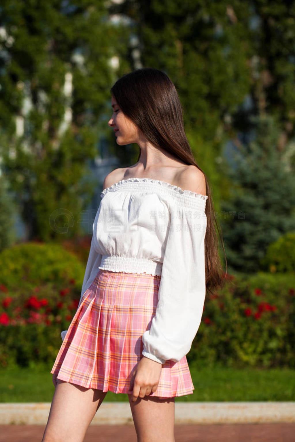 Pretty stylish brunette girl in plaid skirt and white blouse