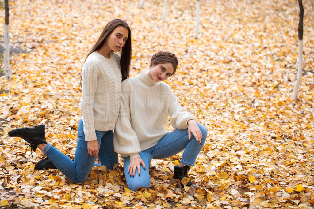 Two girlfriends in a white woolen sweater and blue jeans