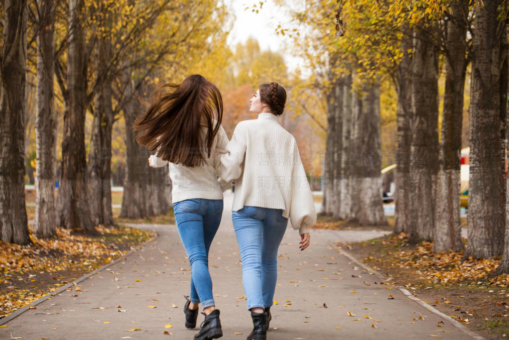 Two girlfriends in a white woolen sweater and blue jeans