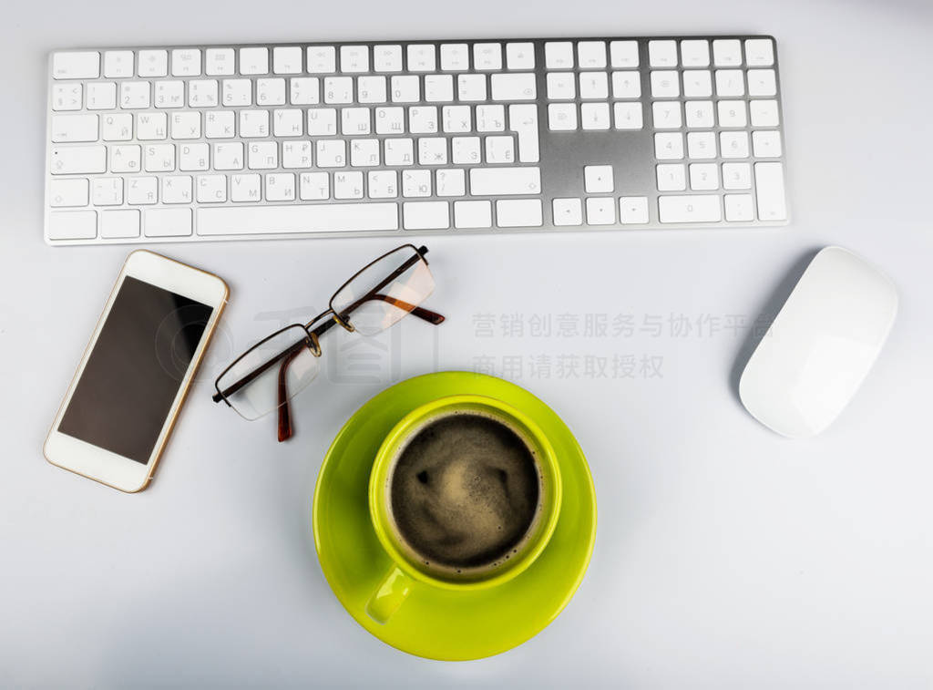 Office desk table with computer keyboard, phone and coffee cup.