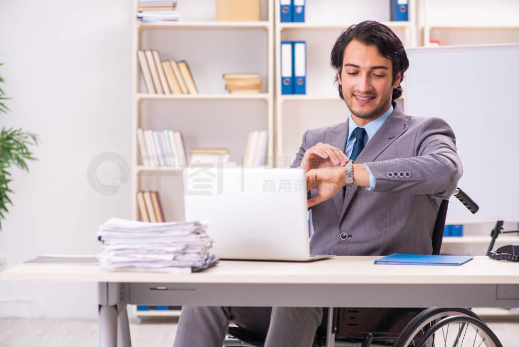 Young handsome employee in wheelchair at the office