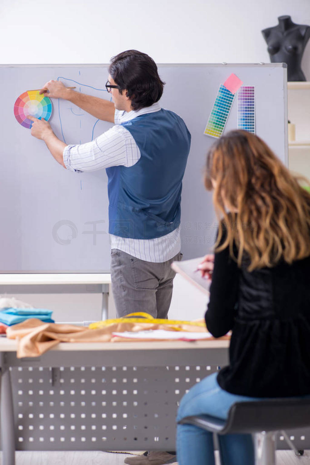 Young male tailor teaching female student