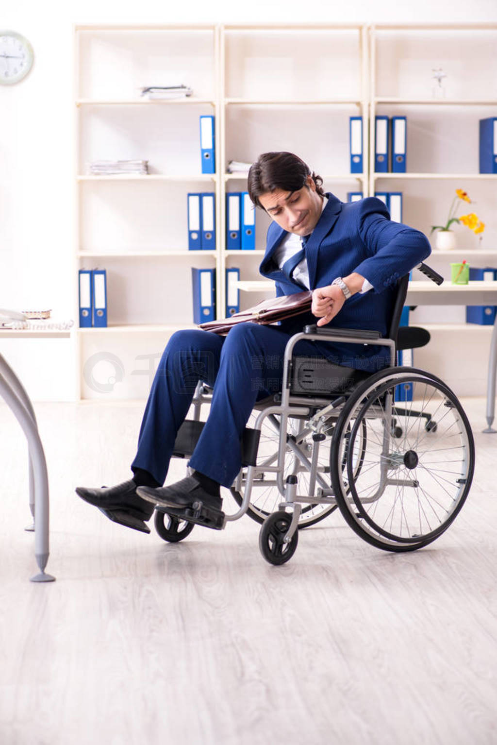 Young male employee in wheelchair working in the office