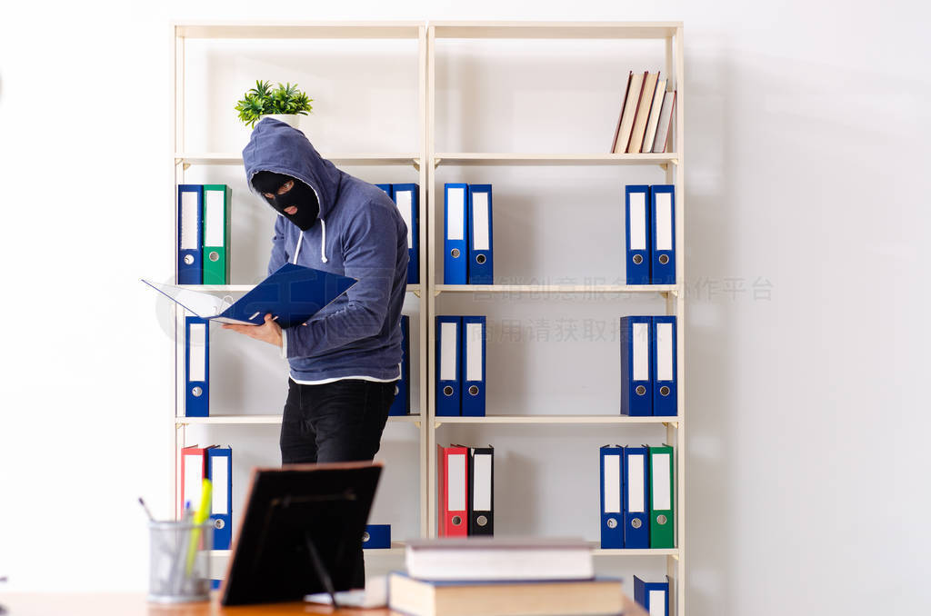 Male thief in balaclava in the office