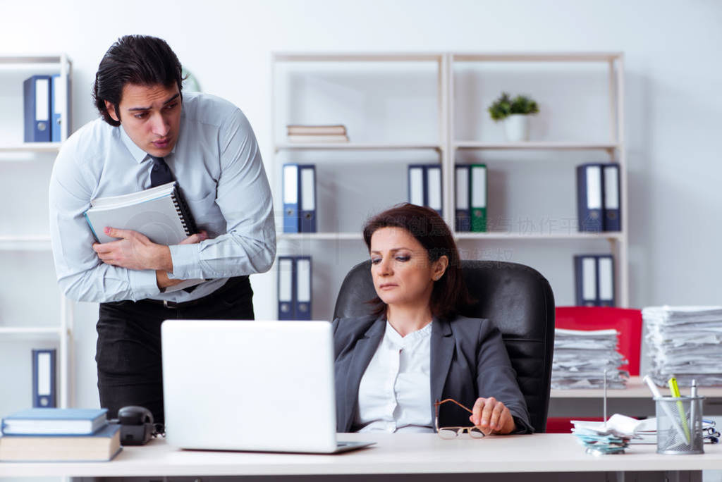 Old female boss and young male employee in the office