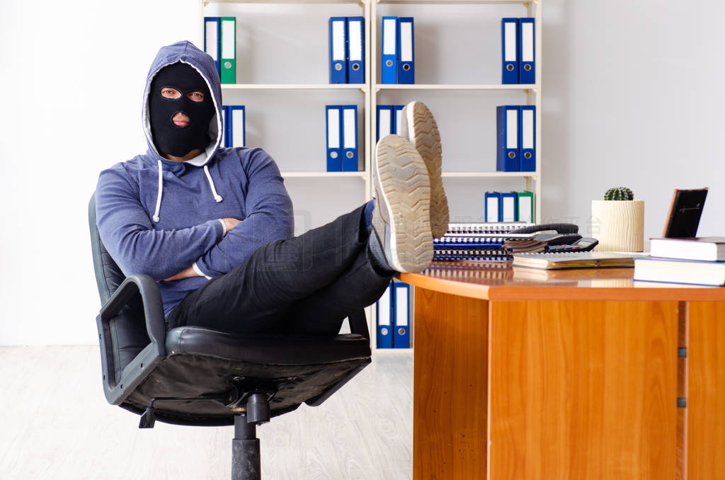 Male thief in balaclava in the office