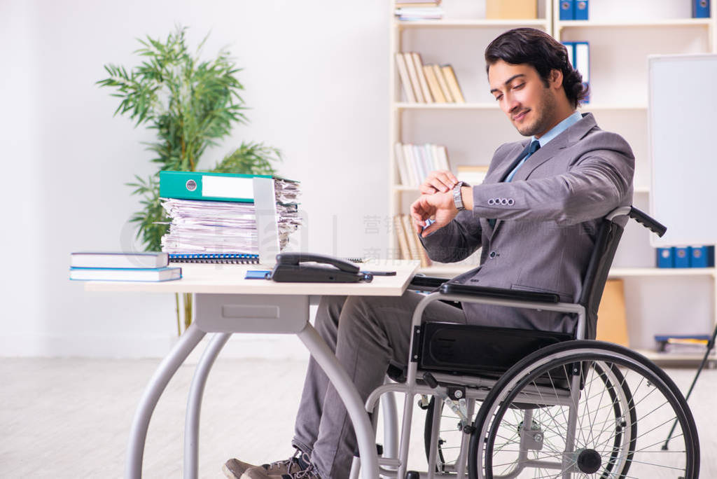 Young handsome employee in wheelchair at the office