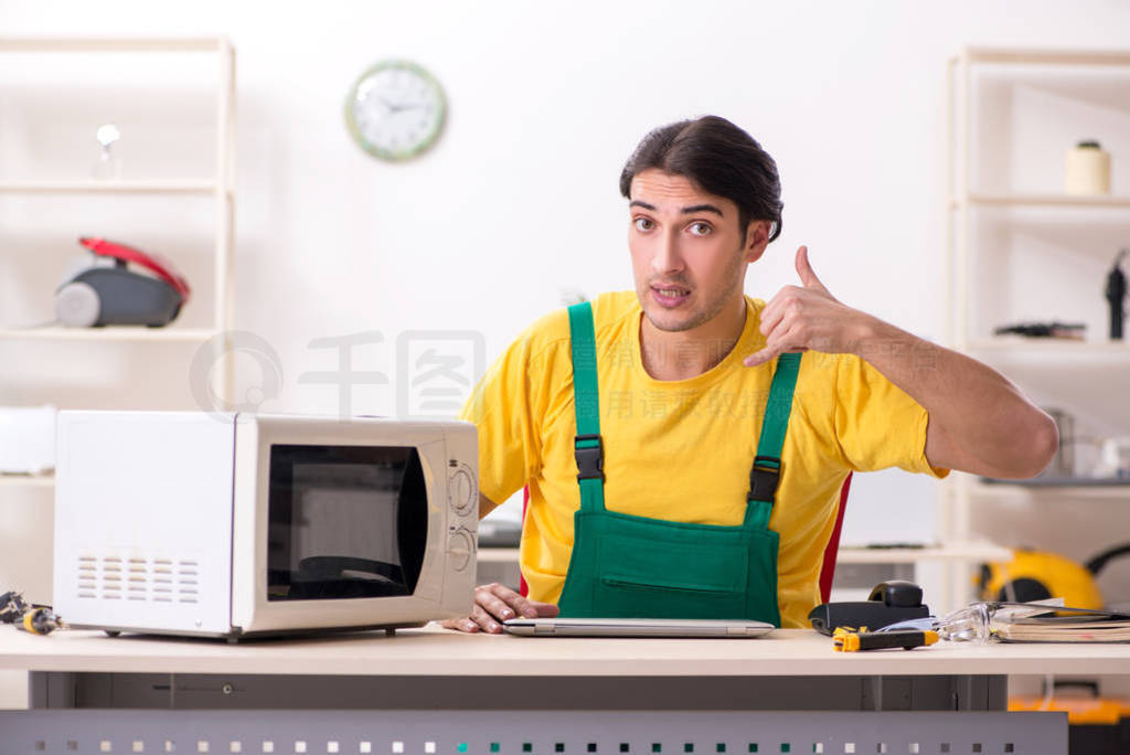 Young repairman repairing microwave in service centre