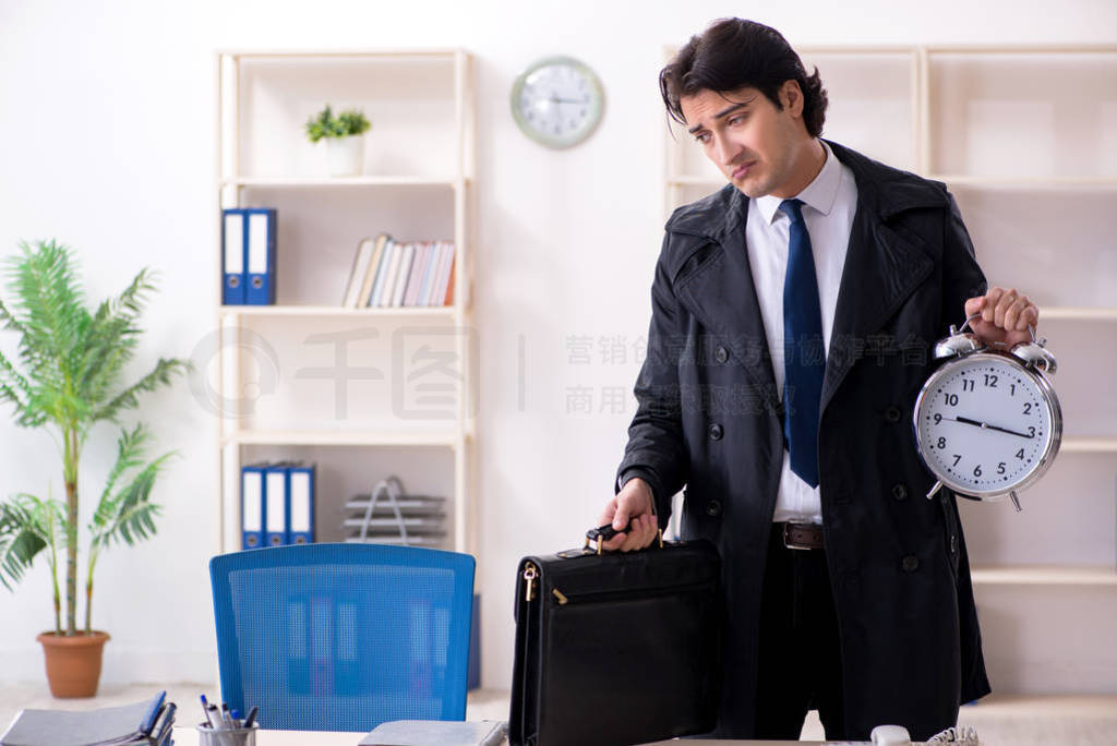 Young male employee in the office in time management concept