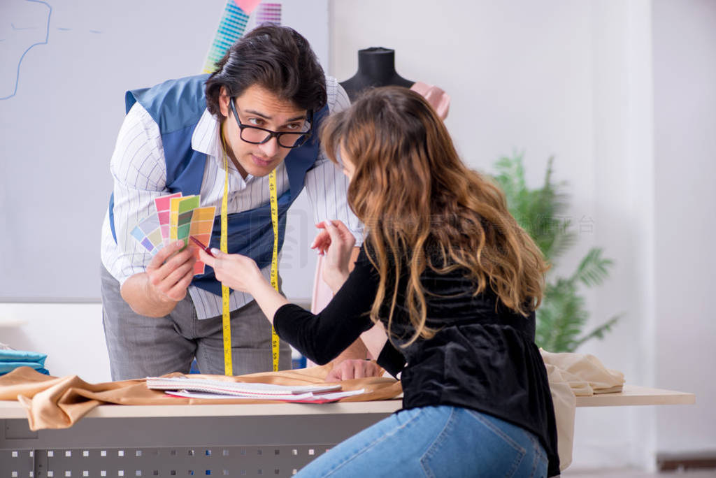 Young male tailor teaching female student