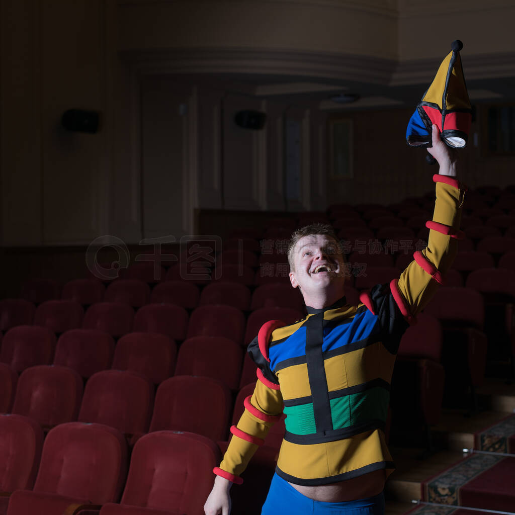 Actor dressed jesters costume in interior of old theater.