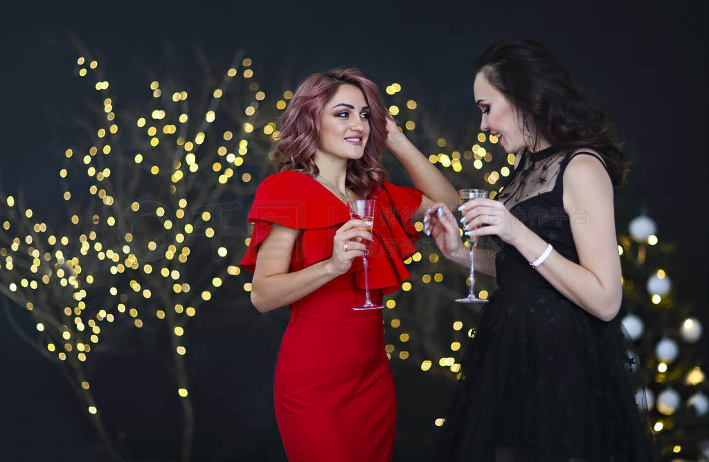 Smiling women in evening dresses with glasses of champagne over