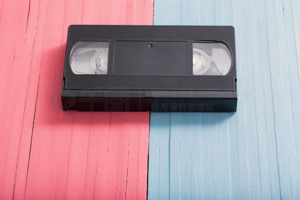 Video cassette on pink and blue wooden background background.