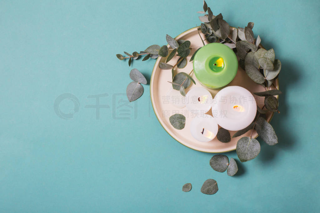 eucalyptus leaves and burning candles on blue background